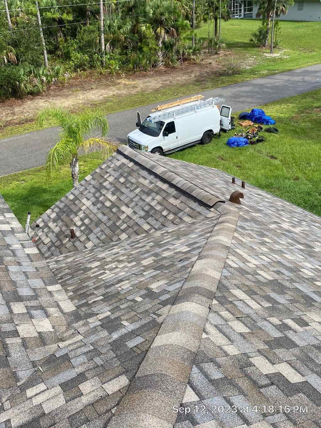 A van is working on a roof in a residential area, performing various tasks.