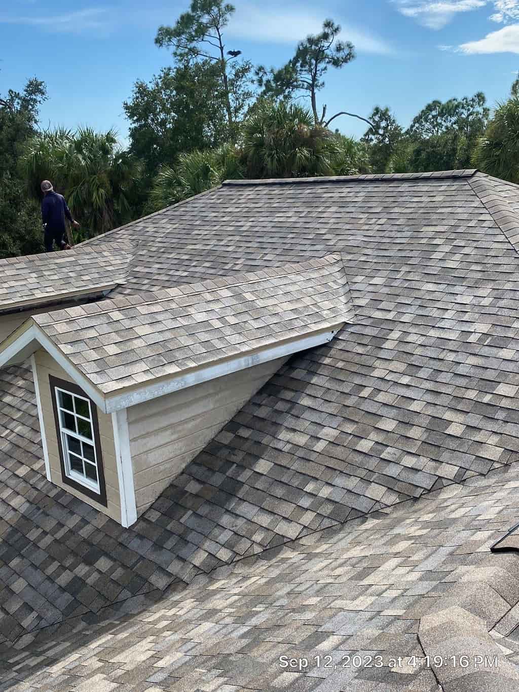 A man is hard at work installing shingles on a roof.
