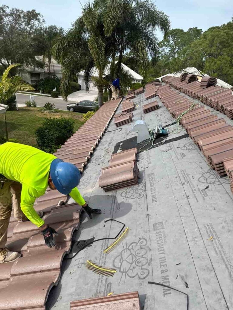 A worker is installing a tile roof on a house.