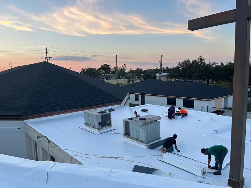 A team of workers is diligently repairing the roof of a church.